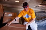 An employee climbs into the cargo hold and begins unloading boxes at OSH.